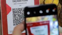 QRIS adalah standar kode QR (Quick Response) yang digunakan di Indonesia untuk menghubungkan dompet digital dan metode pembayaran non-tunai dengan berbagai pihak, termasuk bank dan pedagang. (Liputan6.com/Johan Tallo)