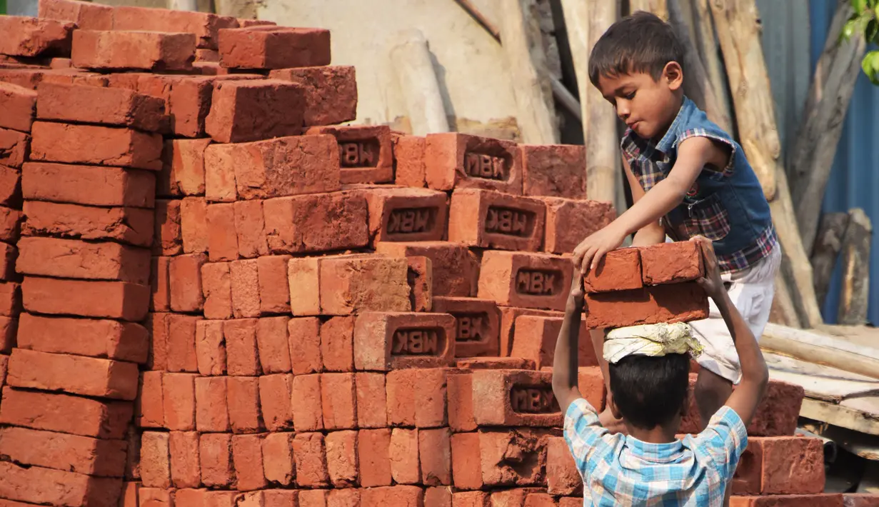 Dua orang anak mengangkat batu batu di sebuah bangunan New Delhi, India, Minggu (19/11). Anak-anak juga bekerja di malam hari, bekerja terlalu lama dan sebagian diperlakukan seperti budak. (DOMINIQUE FAGET)