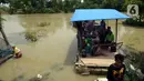 Warga menaiki perahu saat melintasi banjir di Desa Sindangsari, Kabupaten Bekasi, Jawa Barat, Rabu (24/2/2021). Sebagian rumah warga masih terendam banjir yang disebabkan jebolnya tanggul Sungai Citarum dan luapan Sungai Ciherang. (merdeka.com/Imam Buhori)