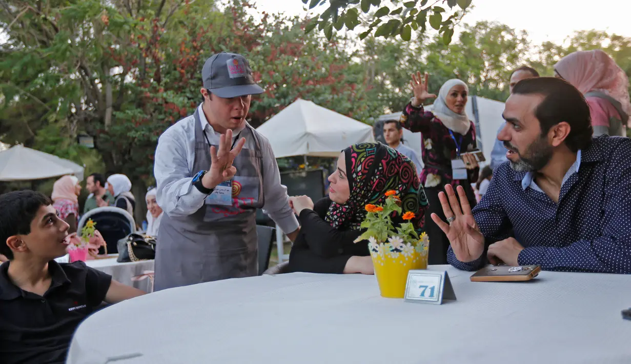 Seorang anak down syndrome Abdel Rahman melayani pelanggan di kedai kopi Sucet  selama festival "Sham gather us" di Damascus (11/7). Enam belas anak laki-laki dan perempuan down syndrome bekerja di Cafe Sucet melayani pelanggan. (AFP Photo/Louai Beshara)