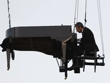 Aksi Pianis Ricardo de Castro Monteiro saat bermain piano sambil tergantung di udara selama Virada Cultural di Brasil (22/6/2015). Virada Cultural merupakan acara budaya 24 jam tanpa gangguan dengan berbagai cara unik.  (AFP PHOTO/Miguel Schincariol)