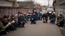Para pelayat berlutut menunggu peti mati Oleksandr Maksymenko (38) lewat saat pemakamannya di kampung halamannya di Kniazhychi, sebelah timur Kyiv, Ukraina, 13 Februari 2023. Oleksandr Maksymenko, seorang warga sipil yang menjadi sukarelawan di angkatan bersenjata Ukraina, tewas dalam pertempuran di daerah Bakhmut. (AP Photo/Emilio Morenatti)