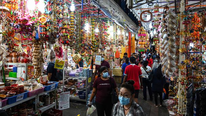 Orang-orang berjalan melintasi sepanjang toko yang menjual ornamen dan dekorasi menjelang Diwali, festival cahaya bagi umat Hindu, di distrik Little India di Singapura pada 23 Oktober 2020. (Photo by Roslan RAHMAN / AFP)