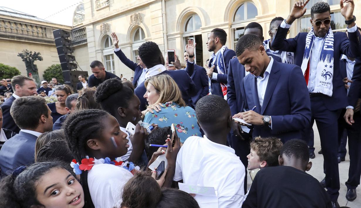 Kylian Mbappe memberikan tandatangan kepada fans cilik di Elysee Presidential Palace, Paris, (16/7/2018). Prancis berpesta merayakan keberhasilan Les Bleus meraih trofi Piala Dunia 2018. (Ludovic Marin/Pool Photo via AP)