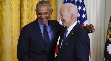 Presiden AS Joe Biden dan mantan Presiden Barack Obama berdiri bersama di atas panggung saat acara tentang Undang-Undang Perawatan Terjangkau, atau biasa disebut Obamacare di East Room Gedung Putih di Washington, 5 April 2022. (AP Photo/Carolyn Kaster)