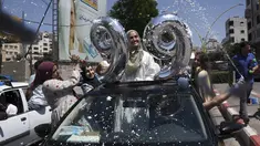 Siswa SMP Palestina menyemprotkan busa dari jendela mobil saat mereka merayakan kelulusan usai mengikuti ujian akhir yang dikenal sebagai "Tawjihi" dengan nilai 99/100, di Kota Hebron, Tepi Barat (3/8/2021). (AFP/Hazem Bader)