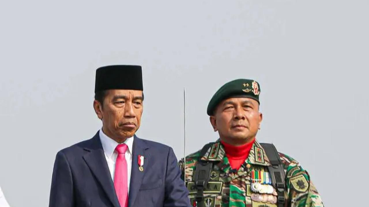 Jokowi terlihat mengenakan peci dan setelan jas hitam. Mantan Gubernur DKI Jakarta itu berdiri di atas tank BMP-3F Korps Marinir.