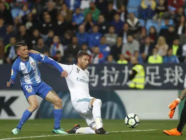 Pemain Real Madrid, Sergio Ramos (tengah) berusaha menghalau bola dari kejaran pemain Malaga, Maxime Lestienne (kiri) pada lanjutan La Liga Santander di Rosaleda stadium, Malaga, (15/4/2018). Madrid menang 2-1. (AP/Miguel Morenatti)