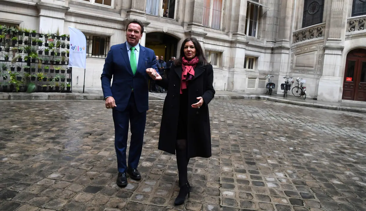 Gubernur California ke-38, Arnold Schwarzenegger menggandeng Walikota Paris, Anne HIdalgo di Paris (11/12). Schwarzenegger berada di Paris untuk menghadiri pertemuan puncak iklim One Planet. (AFP Photo / Alain Jocard)