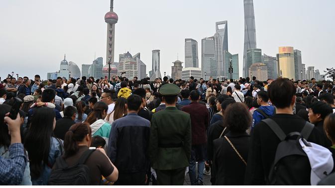 Warga mengunjungi kawasan Bund di sepanjang Sungai Huangpu selama liburan May Day di Shanghai pada 1 Mei 2019 (atas) dan warga mengenakan masker di tengah kekhawatiran virus corona COVID-19 di tempat yang sama pada 8 Maret 2020. (Hector RETAMAL/AFP)