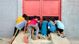 Sejumlah anak mengintip sesi latihan Persija di lapangan indoor, Sawangan, Depok. (Bola.com/M Iqbal Ichsan)