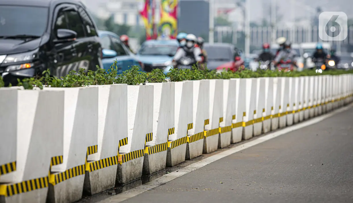 Kendaraan melintas di samping jalur khusus sepeda yang diberikan pembatas jalur permanen di Jalan Sudirman, Jakarta, Kamis (17/6/2021). Kapolri Jenderal Listyo Sigit Prabowo akan membongkar jalur sepeda di Sudirman-Thamrin dan mempelajari jalur sepeda di negara lain. (Liputan6.com/Faizal Fanani)
