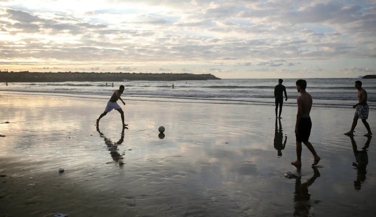 Anak laki-laki bermain bola saat matahari terbenam jelang waktu berbuka puasa di pantai Rabat, Maroko (9/6). Selama Ramadan, banyak warga Maroko berkunjung ke pantai menikmati angin Atlantik dan menikmati pemandangan laut. (AP Photo/Mosa'ab Elshamy)