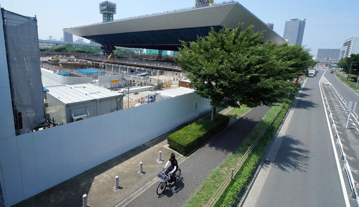 Pesepeda melintas dekat Olympic Aquatics Center selama tur media ke sejumlah venue Olimpiade Tokyo 2020 di Tokyo, Selasa (17/7). Nantinya cabang Olahraga akuatik termasuk berenang, menyelam dan renang artistik akan berlangsung di sini. (AP/Eugene Hoshiko)