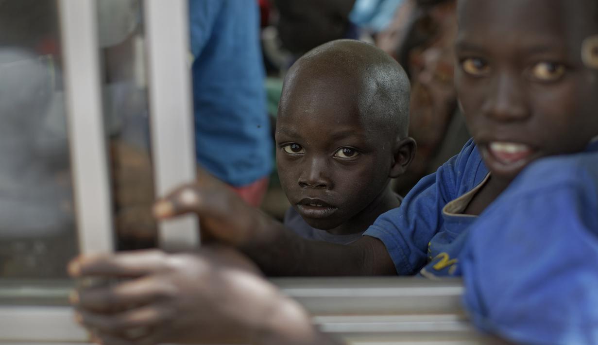 Sejumlah anak Sudan Selatan berada di dalam bus yang akan membawa mereka ke pusat transit pengungsi di Kuluba, Uganda utara, Kamis (8/6). (AP Photo / Ben Curtis)