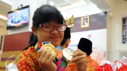 Atlet Special Olympics Indonesia (SOIna), Tiffany Angeline Rusli memamerkan medali yang diperolehnya dari cabang renang di Special Olympics World Summer Games (SOWSG) XIV di Amerika Serikat, Jakarta, Rabu (5/8/2015). (Liputan6.com/Helmi Fithriansyah)