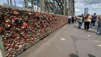 Menyusuri Jembatan Hohenzollern yang berada di atas Sungai Rhein di Kota Koln, Jerman. Ada begitu banyak gembok yang dipasang di pagar pembatas antara rel kereta api dan trotoar pejalan kaki. (Bola.com/Benediktus Gerendo Pradigdo)