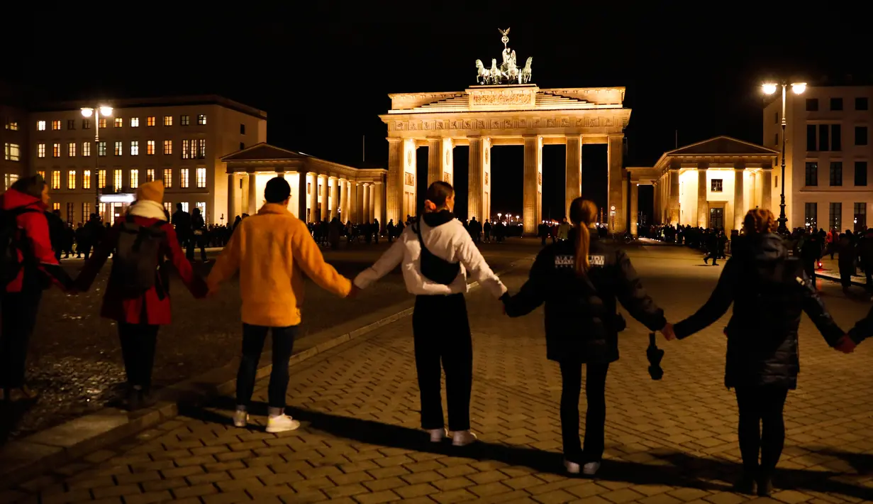Warga membentuk rantai manusia saat berkabung untuk para korban penembakan brutal di Hanau di Gerbang Brandenburg Berlin, Jerman, Kamis (20/2/2020). Polisi masih menyelidiki keterlibatan orang lain dalam penembakan tersebut. (AP Photo/Markus Schreiber)