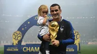 Pemain depan Prancis, Antoine Griezmann berpose dengan putrinya sambil membawa trofi Piala Dunia di Stadion Luzhniki, Moskow, Rusia, 15 Juli 2018. Griezmann masuk dalam kandidat pemain terbaik FIFA 2018. (AFP FOTO/FRANCK FIFE)