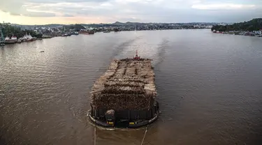 Sebuah kapal tongkang berisi kayu gelondongan ditarik di sepanjang Sungai Mahakam melewati Kota Samarinda, Kalimantan Timur, 4 November 2021. (ADITYA AJI/AFP)