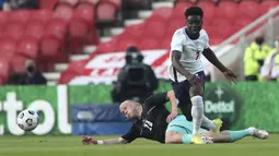 Striker Inggris, Bukayo Saka (kanan) berebut bola dengan gelandang Austria, Xaver Schlager dalam laga uji coba menjelang berlangsungnya Euro 2020 di Riverside Stadium, Middlesbrough, Rabu (2/6/2021). Inggris menang 1-0 atas Austria. (AP/Scott Heppell/Pool)