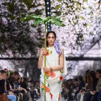 Alih-alih menampilkan kemewahan couture secara konvensional, Anderson mengubah ruang peragaan yang berlokasi di Musée Rodin menjadi lanskap yang terasa hidup. Bunga-bunga digantung di udara, menciptakan kesan seolah alam perlahan mengambil alih ruang couture. [Dok/DIOR].