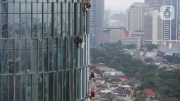Pekerja membersihkan kaca gedung bertingkat di Jakarta, Jumat (26/02/2021). BP Jamsostek menekankan dua aspek penting terkait pandemi Covid-19, yakni isu kesehatan dan perekonomian dengan jaminan sosial bagi para pekerja dan penerapan K3. (Liputan6.com/Fery Pradolo)