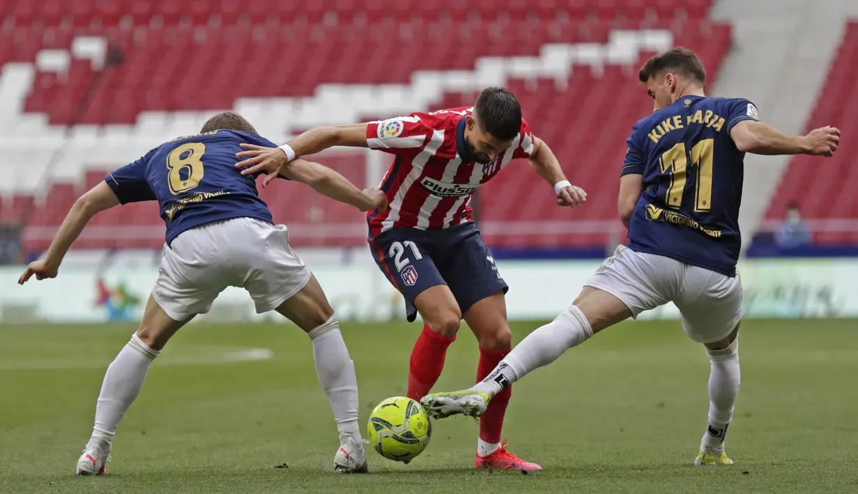 Gelandang Atletico Madrid, Yannick Carrasco (tengah) bersaing dengan pemain Osasuna, Darko Brasanac dan Enrique Barja pada laga pekan ke-37 LaLiga di Wanda Metropolitano, Minggu (16/5/2021). Sempat tertinggal,  Atletico Madrid menang dramatis 2-1 atas Osasuna. (AP Photo/Manu Fernandez)