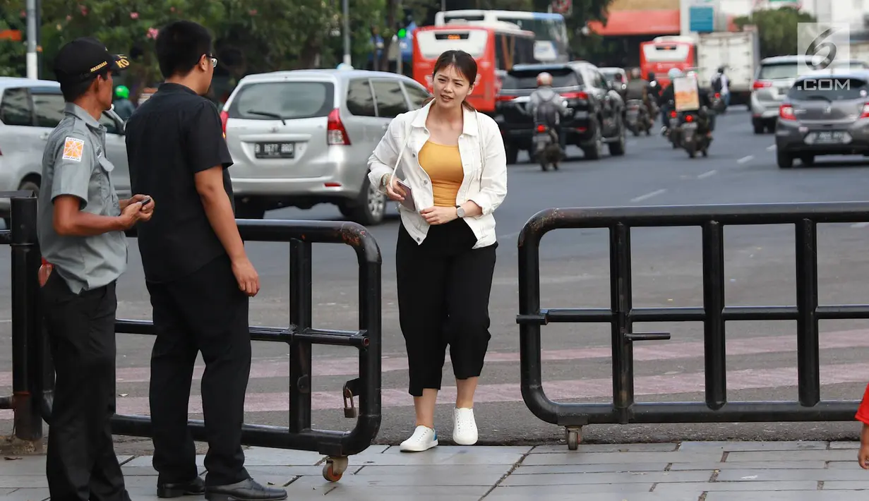 Pejalan kaki melintasi jalur masuk dan keluar Taman Fatahilah, Kota Tua, Jakarta, Selasa (23/4). Unit Pengelola Kawasan (UPK) Kota Tua melakukan uji coba simulasi pengaturan alur pintu masuk dan pintu keluar ke Taman Fatahillah bagi pejalan kaki selama dua minggu. (Liputan6.com/Immanuel Antonius)