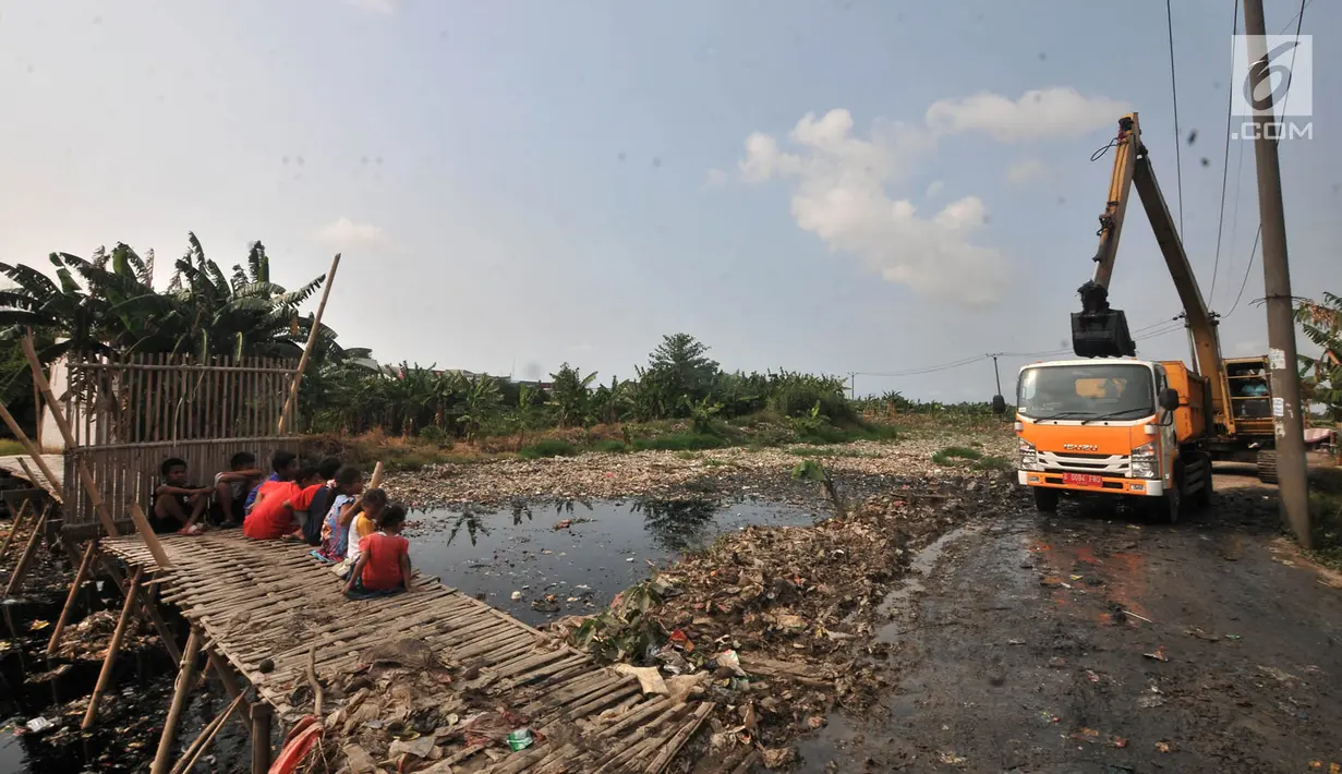 Anak-anak menyaksikan pengerukan sampah Kali Pisang Batu, Tarumajaya, Bekasi, Jawa Barat, Rabu (9/1). Petugas DLH Kabupaten Bekasi mulai membersihkan sampah setelah fenomena tersebut ramai diberitakan di media sosial. (Merdeka.com/Iqbal S. Nugroho)