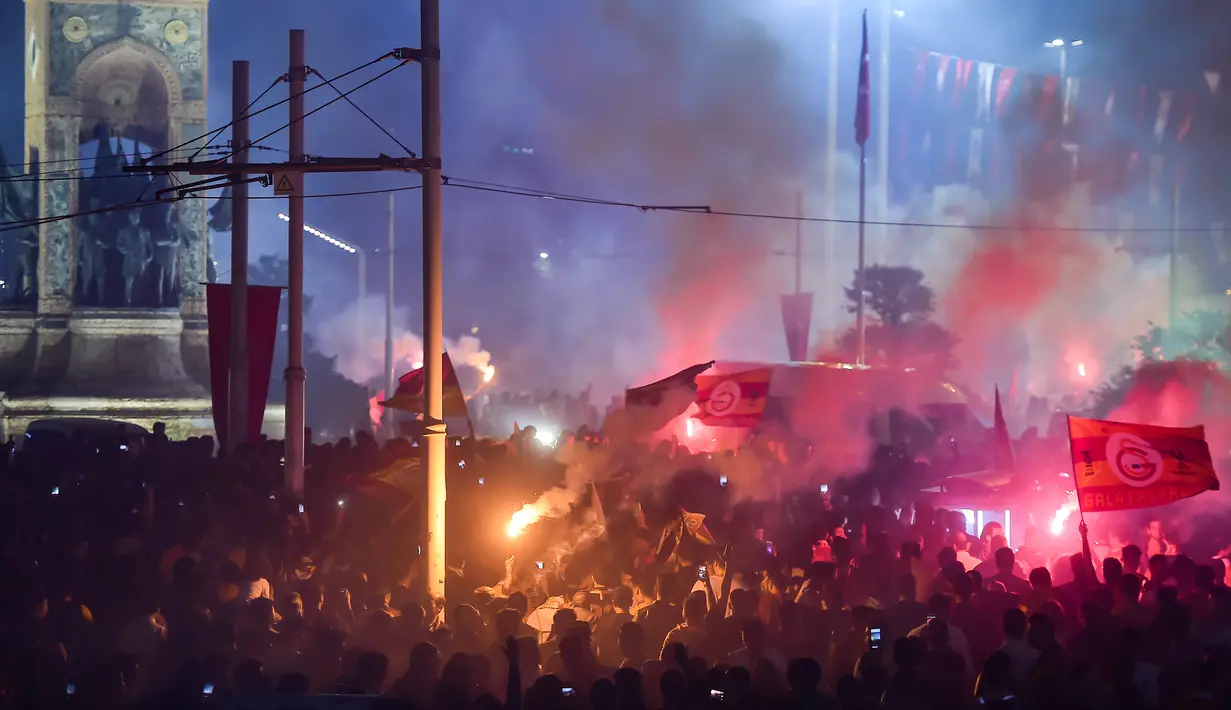 Suporter Galatasaray menyalakan flare saat merayakan kemenangan timnya meraih gelar Liga Turki usai pertandingan melawan Istanbul Basaksehir di Turk Telekom Arena di Istanbul (19/5/2019). Galatasaray memastikan gelar liga Turki ke-22 usai mengalahkan Istanbul Basaksehir 2-1. (AFP Photo/Yasin Akgul)