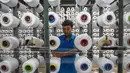 Seorang pekerja mengatur gulungan benang untuk alat tenun di pabrik Trisula Textile Industries di Cimahi, Jawa Barat pada 15 April 2025. (TIMUR MATAHARI/AFP)