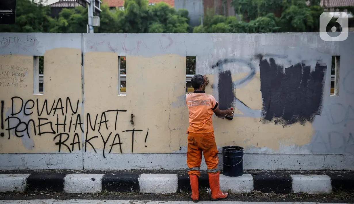 Petugas PPSU membersihkan coretan yang mengotori pembatas jalan pascaunjuk rasa di kawasan DPR/MPR, Jakarta, Jumat (17/7/2020). Coretan tersebut dilakukan oleh massa yang menolak RUU Omnibus Law Cipta Lapangan Kerja di depan Gedung DPR pada Kamis (16/7) kemarin. (Liputan6.com/Faizal Fanani)