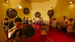 Sejumlah orang berdoa memperingati korban serangan paris di dalam air panas dengan air berwarna anggur di resor spa Hakone Kowaki-en Yunessun saat Beaujolais Nouveau Day di Hakone barat Tokyo,Jepang (19/11). (REUTERS/Thomas Peter)