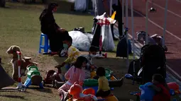 Anggota keluarga berada di taman bermain Institut Pengembangan Sumber Daya Manusia Nasional di Jincheon, Korea Selatan (13/10/2021). Para pengungsi muncul di hadapan publik pada hari Rabu, untuk pertama kalinya sejak mereka tiba pada akhir Agustus. (AFP/Pool/Jeon Heon-kyun)