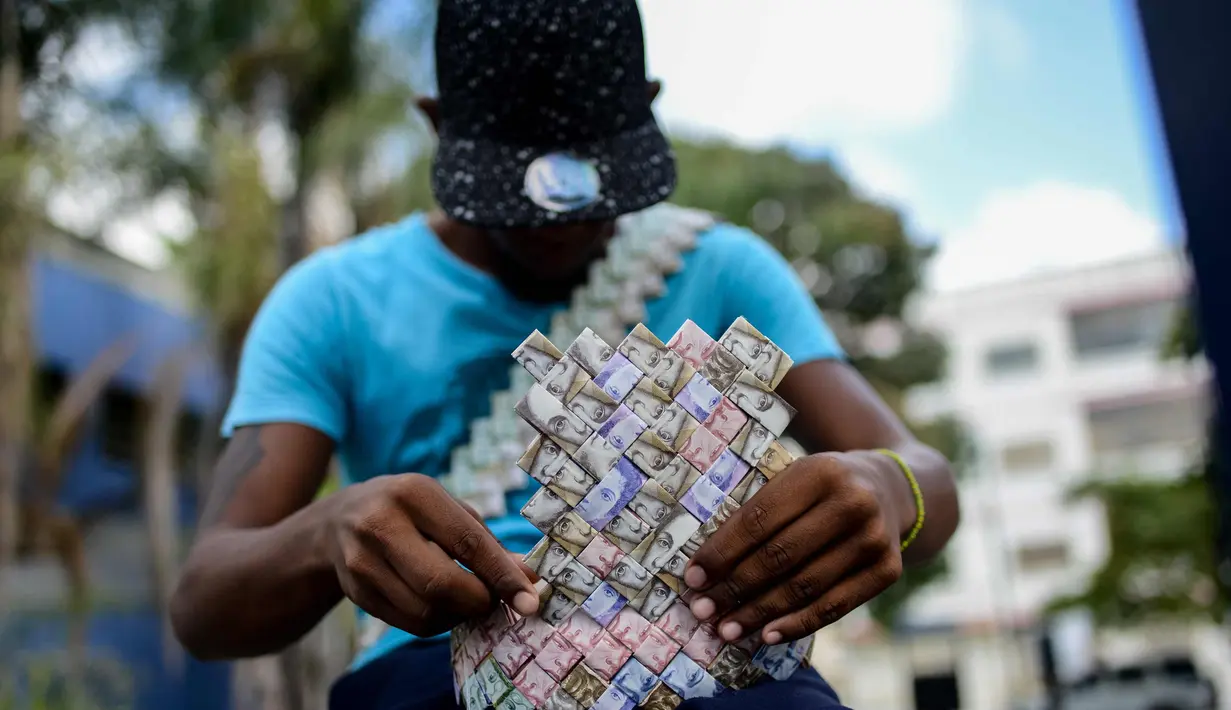 Wilmer Rojas (25) saat membuat tas dari lembaran mata uang Bolivar di Caracas, Venezuela, 30 Januari 2018. Lembaran uang tersebut kini tidak lagi menjadi alat jual beli, melainkan bahan untuk membuat kerajinan tangan. (AFP Photo/Federico Parra)
