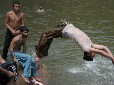 Sejumlah pria bermain di sungai saat siang hari saat Ramadan di Islamabad, Pakistan, Senin (5/6). Suhu di Pakistan pada siang hari mencapai 43 derajat celcius. (AFP PHOTO / AAMIR QURESHI)