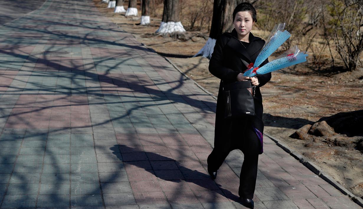 Seorang wanita membawa bunga saat menandai Hari Perempuan Internasional di Pyongyang, Korea Utara, Jumat (8/3). Hari Perempuan Internasional jatuh pada tanggal 8 Maret setiap tahunnya. (AP Photo/Dita Alangkara)