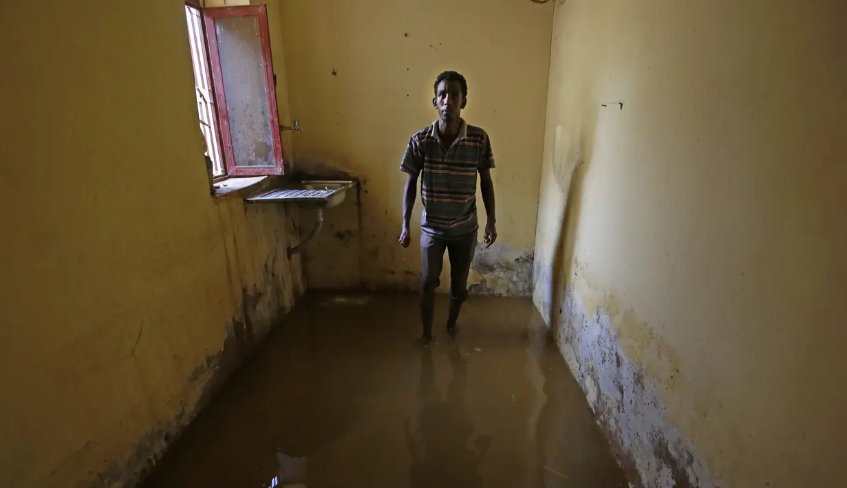 Seorang pemuda Sudan berdiri di dalam ruangan banjir di daerah alqamayir di kota kembar ibu kota Omdurman (26/8/2020). (AFP Photo/Ashraf Shazly)