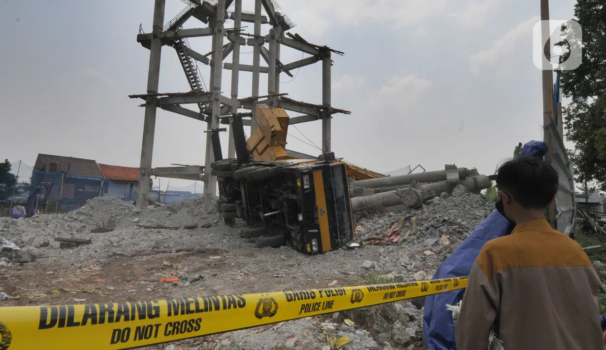Warga melihat truk crane yang terguling dan menimpa rumah warga di di Jalan Mawar, Perumnas Depok Jaya, Depok, Jawa Barat, Jumat (15/10/2021). Truk crane di kawasan Proyek PDAM terguling dan menimpa rumah menyebabkan tiga warga mengalami luka serius. (merdeka.com/Arie Basuki)
