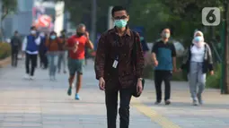 Seorang pria yang mengenakan baju batik berjalan di kawasan Thamrin Sudirman, Jakarta, Jumat (2/10/2020). Pada Hari Batik Nasional yang berlangsung di tengah pandemi COVID-19, sebagian masyarakat terlihat mengenakan baju dan masker dengan motif batik. (merdeka.com/Imam Buhori)