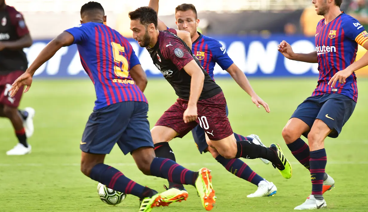 Gelandang AC Milan Hakan Calhanoglu berusaha melewati tiga pemain Barcelona saat bertanding pada International Champions Cup di Levi's Stadium di Santa Clara, California (4/8). Milan menang tipis 1-0 atas Barcelona. (AFP Photo/Lachlan Cunningham)