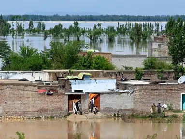 Orang-orang berdiri di rumah mereka yang terendam banjir setelah hujan lebat di distrik Nowshera, Provinsi Khyber-Pakhtunkhwa, Pakistan pada tanggal 16 April 2024. (Abdul MAJEED/AFP)