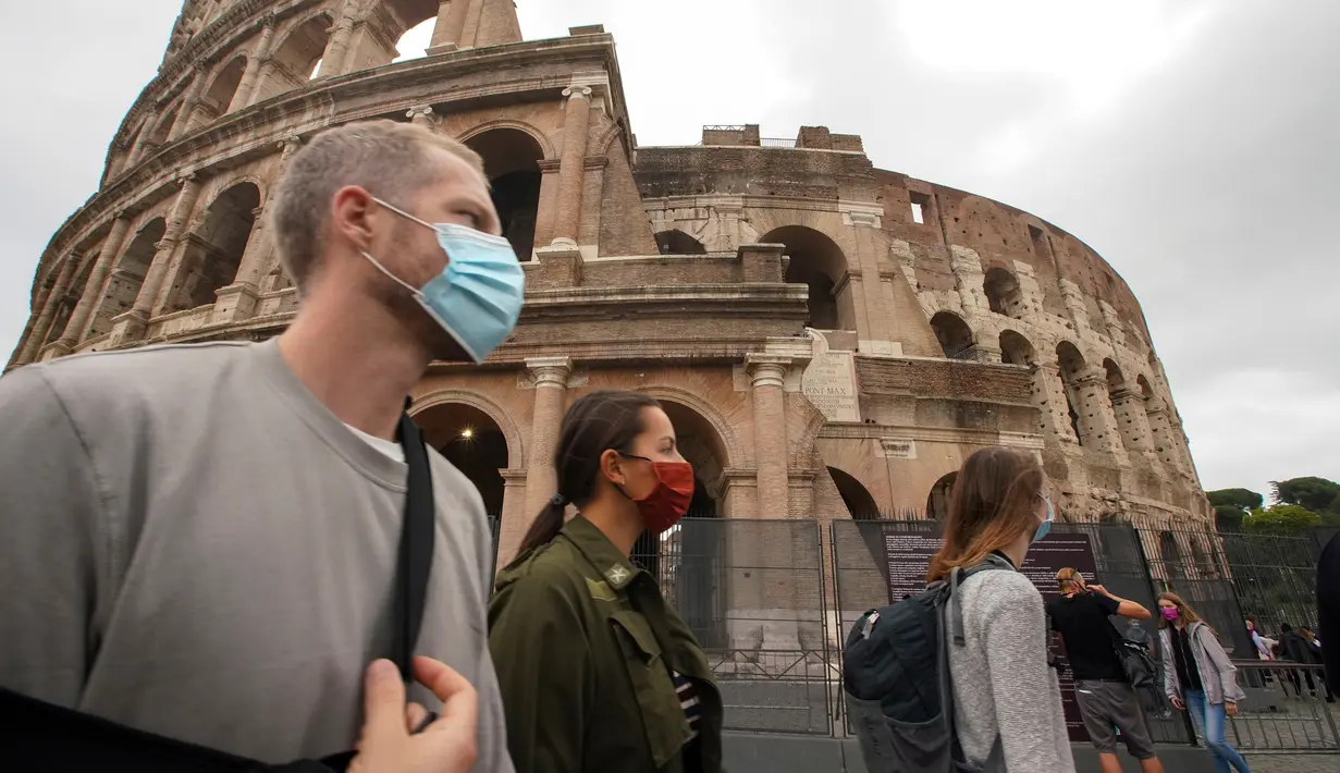 Orang-orang memakai masker untuk mencegah penyebaran COVID-19 saat mereka berjalan-jalan di dekat Colosseum, di Roma pada Sabtu (3/10/2020). Masker wajah harus dipakai setiap saat di luar rumah di ibu kota Italia Roma dan wilayah sekitar Lazio mulai Sabtu, 3 Oktober. (AP Photo/Andrew Medichini)