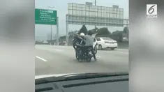 Seorang pengendara motor nekat membonceng seorang penumpang dan juga sebuah motor di jalanan ramai.