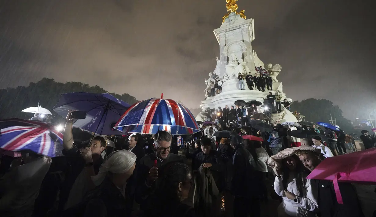 Para pelayat di Peringatan Ratu Victoria di luar Istana Buckingham di pusat kota London, menyusul pengumuman meninggalnya Ratu Elizabeth II, Kamis, 8 September 2022. Selama hidupnya, Ratu Elizabeth II dikenal memiliki kesehatan yang baik, meski kemudian sempat terkena COVID-19.  (Yui Mok/PA via AP)