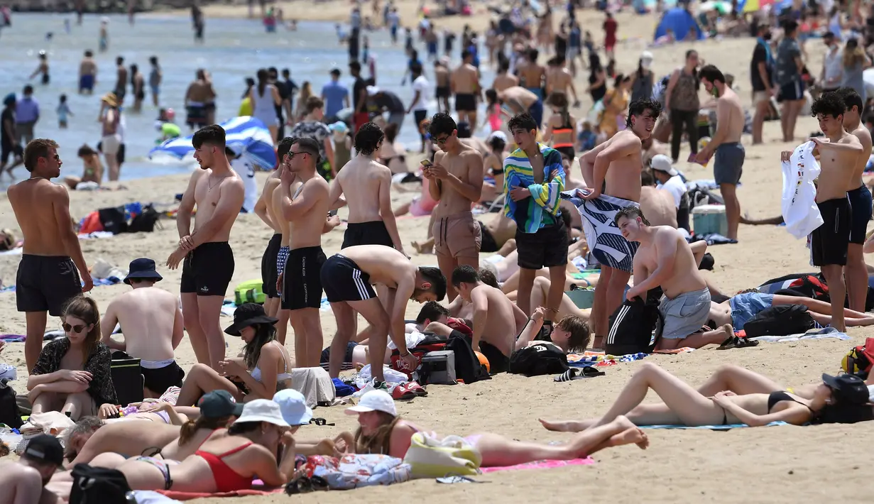 Wisatawan berjemur saat menikmati cuaca hangat di Pantai St Kilda Melbourne, Australia, Selasa (3/11/2020). Negara bagian Victoria di Australia mencatat nol kasus penularan COVID-19 selama empat hari berturut-turut setelah berjuang melawan gelombang kedua wabah pandemi. (AFP/William West)
