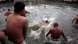 Umat Hindu Nepal menceburkan ke air untuk penyucian diri saat hari terakhir festival Madhav Narayan di Bhaktapur, Nepal (31/1). Sebelum hari ritual ini, mereka melakukan puasa sebulan penuh. (AP Photo / Niranjan Shrestha)