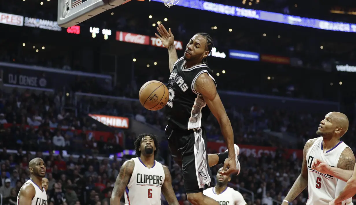 Ekspresi pemain San Antonio Spurs, Kawhi Leonard (tengah) saat memasukan bola melewati hadangan para pemain L. A. Clippers pada laga NBA basketball game di Staples Center, (22/12/2016). Clippers menang 106-101. (AP/Jae C. Hong)