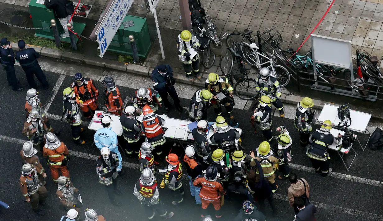 Petugas pemadam kebakaran bekerja di depan sebuah gedung, tempat kebakaran terjadi di Osaka (17/12/2021). Polisi masih menyelidiki penyebab kebakaran lantai empat di bangunan berlantai delapan tersebut. (AFP/STR/Jiji Pers)